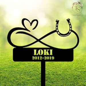 May include: Black metal garden stake with an infinity symbol, a heart, and a horseshoe. The stake has a black sign with the text "LOKI 2012-2019".
