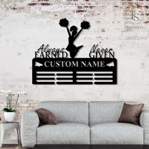 May include: Black metal medal display with a cheerleader silhouette, pom-poms, and the text "Always Earned Never Given". The display has a space for a custom name and 10 medal slots.