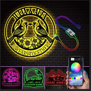 May include: A personalized LED sign with the names "Julia & Alex" and "30 Years Together" in a circular design, featuring two birds and flowers. Includes a USB cable and a smartphone displaying a color wheel.