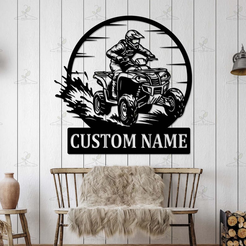 May include: Black metal wall art featuring an ATV rider within a circular frame. The ATV is depicted in motion, with a splash effect. Below the image is the text "CUSTOM NAME" in white letters, perfect for personalization.