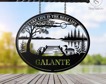 May include: Black metal oval sign with a lake scene, a dock, and a loon. The sign reads "Lake Life is the Best Life" and "GALANTE".