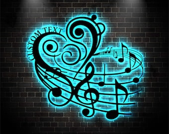 Puede incluir: Arte de pared de metal negro con un diseño de notas musicales en forma de corazón, con las palabras "CUSTOM TEXT" en el lado izquierdo. El diseño está iluminado con un resplandor de neón azul brillante contra una pared de ladrillos oscuros.