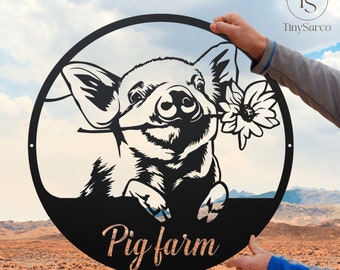 May include: Black metal circular sign with a cutout of a pig holding a flower. The sign says "Pig farm" in a copper-colored font.