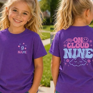 May include: A purple t-shirt with the text "9" and "NAME" with star graphics. The back of the shirt has the words "ON CLOUD NINE" with a rainbow, smiley face, cloud, and star graphics. The shirt is worn by a young person.