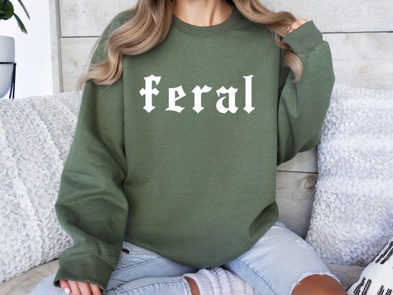 May include: A green sweatshirt with the word "feral" printed in white on the front. The sweatshirt is made of a soft, comfortable material and has a relaxed fit.