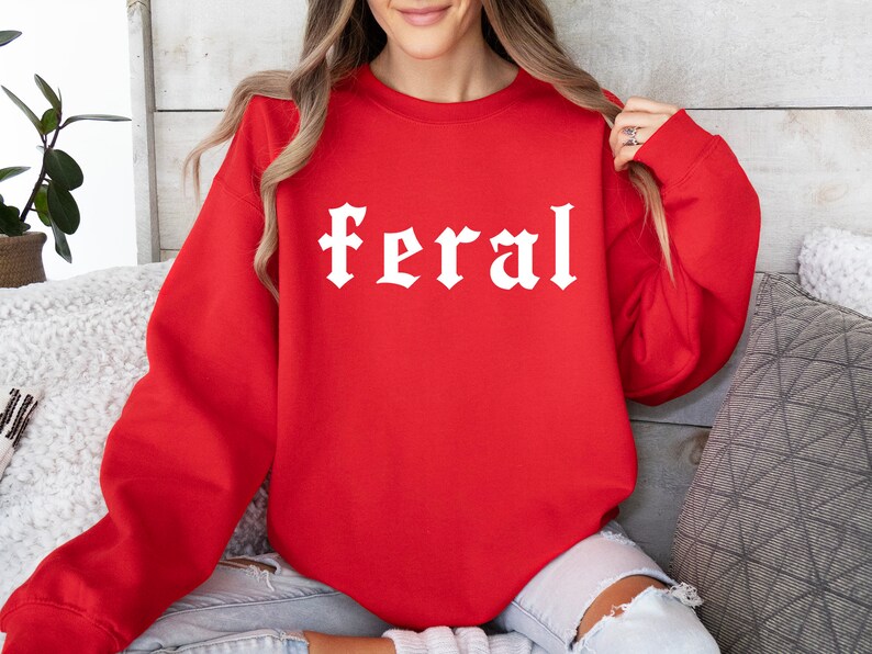 May include: Red sweatshirt with the word "feral" printed in white in a gothic font.