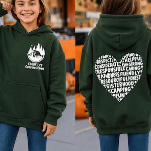 May include: Dark green hooded sweatshirt with a front pocket and a white graphic of a tent and trees. The text "TROOP 128 Custom Name" is below the graphic. The back of the sweatshirt has a heart-shaped design with words like "Camping" and "Fun".