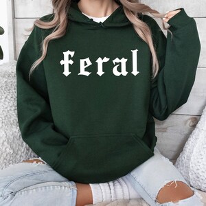 May include: A dark green hooded sweatshirt with the word "feral" printed in white on the front.