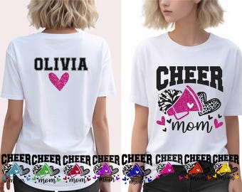 May include: White t-shirts with black text and pink accents. One shirt says "OLIVIA" with a pink heart. The other says "CHEER mom" with a megaphone, hearts, and pom-poms. Cheerleading apparel.