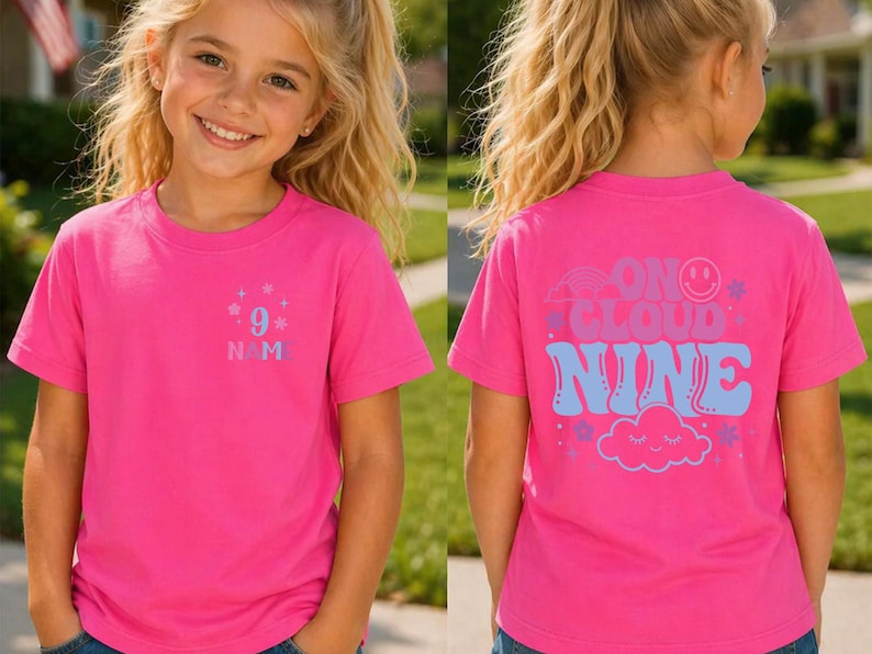 May include: A bright pink t-shirt with the text "9" and "N M" on the front. The back of the shirt features the phrase "On Cloud Nine" with a rainbow, smiley face, stars, and a cloud graphic. The shirt is short-sleeved.