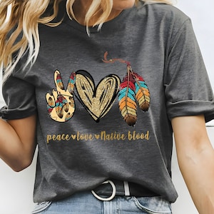 May include: Gray t-shirt with a peace sign, heart, and feathers graphic. The text "peace love native blood" is printed below the graphic.