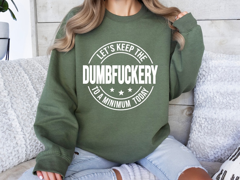 May include: A green sweatshirt with a white circle graphic that says "Let's Keep the Dumbfuckery to a Minimum Today".