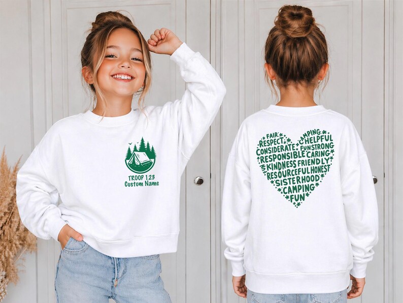 May include: White sweatshirt with a green camping graphic and text "TROOP 123 Custom Name" on the front. The back features a green heart-shaped design with words like "FAIR", "RESPECT", and "CAMPING".