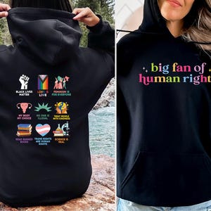 May include: Black hoodies with graphic text and symbols. One hoodie says "big fan of human rights" in rainbow colors. The other hoodie has various symbols and phrases including "Black Lives Matter" and "Love is Love".