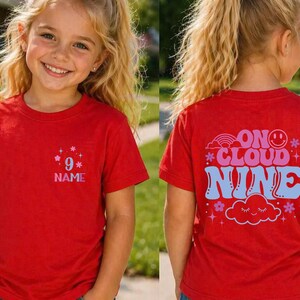 May include: Red t-shirt with the text "9" and "NAME" on the front. The back of the shirt features the phrase "ON CLOUD NINE" with a rainbow, cloud, and star graphics. The shirt is designed for children.