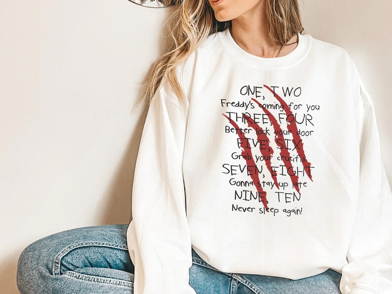 May include: White sweatshirt with the text "ONE, TWO Freddy's coming for you THREE, FOUR Better lock your door FIVE SIX Grab your crucifix SEVEN, EIGHT Gonna stay up late NINE TEN Never sleep again!" and red claw marks.