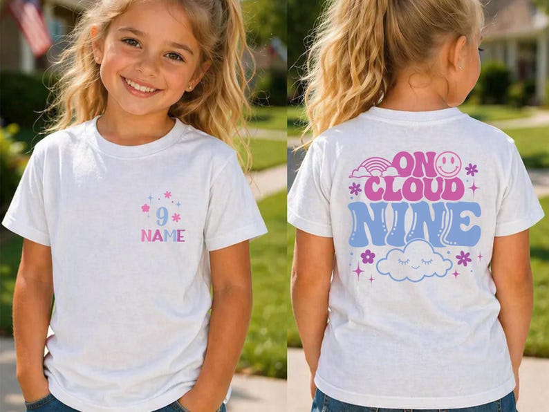 May include: White t-shirt with a colorful design. The front features the number 9 with the word "NAME" below it. The back of the shirt says "ON CLOUD NINE" with a rainbow, cloud, and flower graphics. A fun, casual tee.