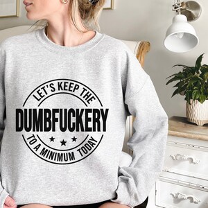 May include: A gray sweatshirt with a black circle graphic that says "Let's Keep The Dumbfuckery To A Minimum Today".