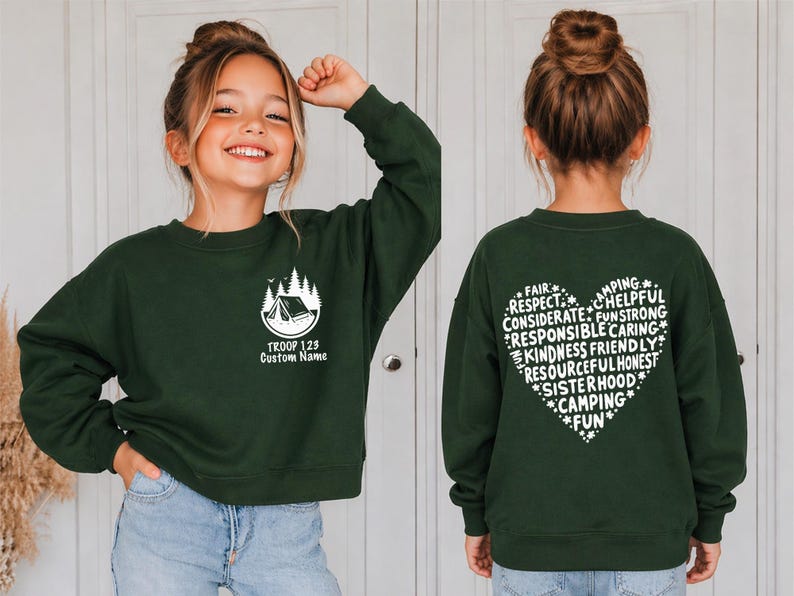 May include: A dark green sweatshirt with a white camping graphic and text. The front features a tent and trees with "TROOP 123 Custom Name". The back displays a heart-shaped design with words like "Fair", "Respect", and "Camping".