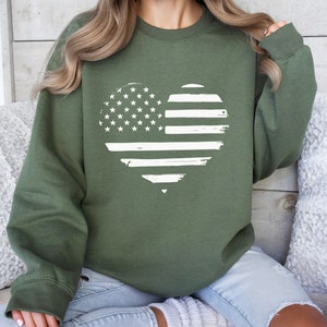 May include: A green sweatshirt with a white distressed American flag heart design.