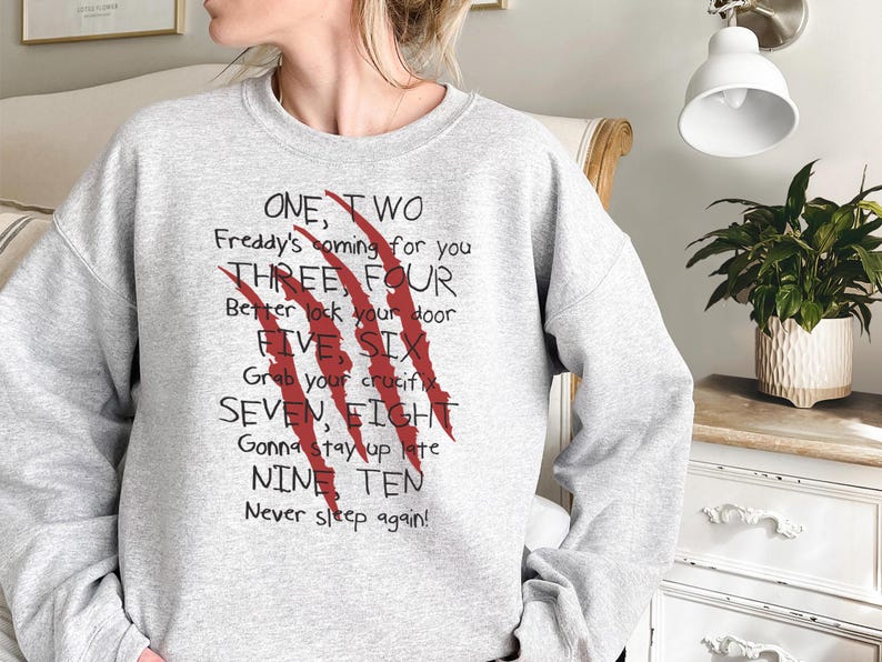 May include: A light gray sweatshirt with the text "ONE, TWO Freddy's coming for you THREE, FOUR Better lock your door FIVE SIX Grab your crucifix SEVEN, EIGHT Gonna stay up late NINE TEN Never sleep again!" and red claw marks.