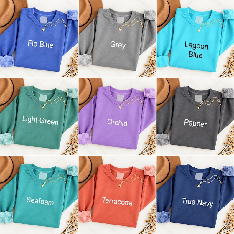 K&ouml;nnte beinhalten: Ein Raster aus neun lang&auml;rmeligen Sweatshirts mit Rundhalsausschnitt in verschiedenen Farben wie Flo Blue, Grey, Lagoon Blue, Light Green, Orchid, Pepper, Seafoam, Terracotta und True Navy. Jedes Sweatshirt hat eine goldene Sternkette.