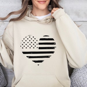 May include: A beige hoodie featuring a black and white heart-shaped American flag design.