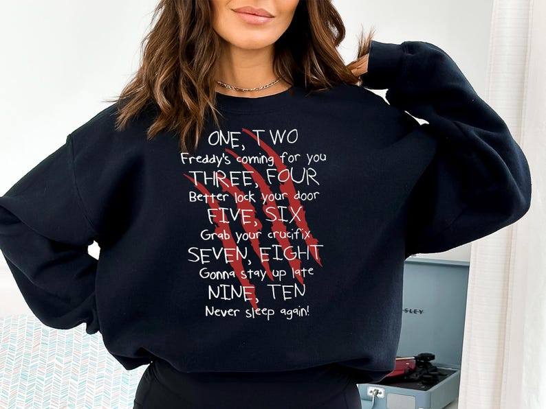 May include: Black sweatshirt with white text and red claw marks. The text reads "ONE, TWO Freddy's coming for you THREE, FOUR Better lock your door FIVE, SIX Grab your crucifix SEVEN, EIGHT Gonna stay up late NINE, TEN Never sleep again!"