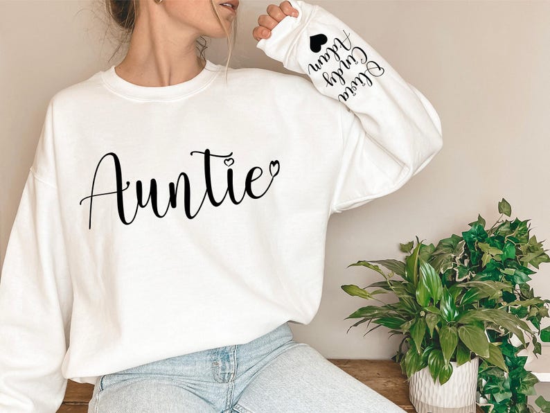 May include: White sweatshirt with the word "Auntie" and a small heart on the front. The sleeves have the words "Little" "Cousin" "Auntie" and a heart printed on them.