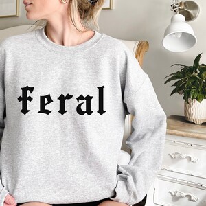 May include: A gray sweatshirt with the word "feral" printed in black gothic lettering.