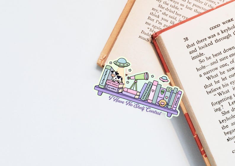 Op de afbeelding: Een kleurrijke sticker met een boekenplankontwerp met boeken, een koe, een telescoop en UFO's. De tekst "I Have No Shelf Control" staat op de sticker, die op een open boek ligt.