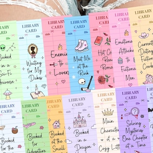May include: A collection of colorful library card-themed bookmarks with various book-related themes and illustrations. Each bookmark features a unique design, including text like "Booked in a Sci-Fi Universe" and "Currently Dating a Fictional Cowboy."