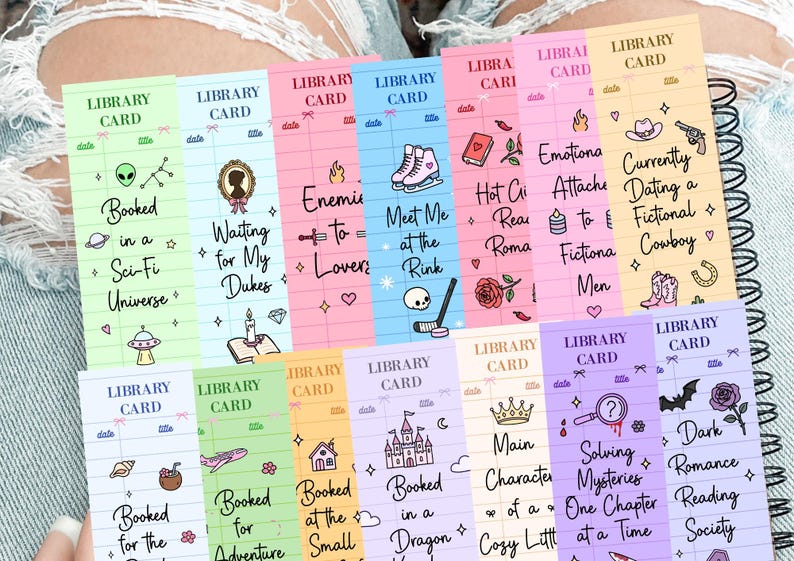 May include: A collection of colorful library card-themed bookmarks with various book-related themes and illustrations. Each bookmark features a unique design, including text like "Booked in a Sci-Fi Universe" and "Currently Dating a Fictional Cowboy."