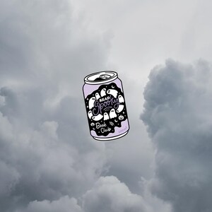 May include: A light purple can with a black label featuring white ghost illustrations and the text "Read Spooky Book Club". The can is set against a cloudy, gray sky.
