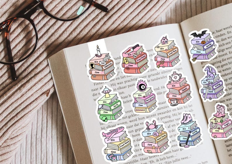 May include: A collection of ten die-cut stickers featuring stacks of books with various thematic icons on top, including a candle, knife, house, bat, UFO, magic eight ball, teapot, dragon, aeroplane, crab, ice skates, and cowboy boots.