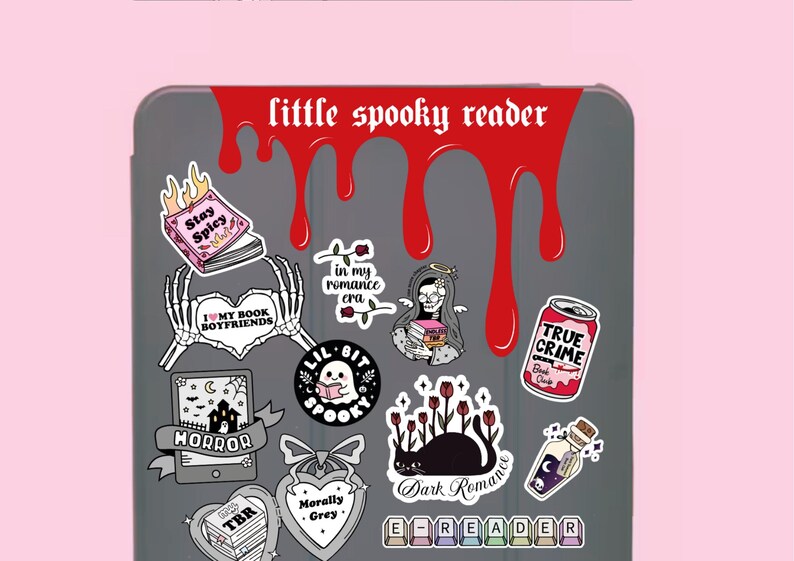 Pode incluir: Uma capa cinzenta para e-reader adornada com autocolantes com temas assustadores. Os autocolantes incluem frases como "Stay Spicy", "True Crime" e "Dark Romance". Um design vermelho gotejante com o texto "little spooky reader" est&aacute; no topo.