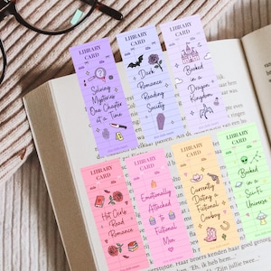 May include: A collection of colorful bookmarks with various themed designs, including a magnifying glass, a bat, a castle, and a cowboy hat. Each bookmark has text like "Solving Mysteries" and "Booked in a Sci-Fi Universe."