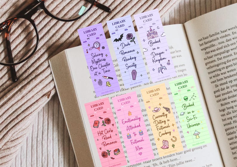 May include: A collection of colorful bookmarks with various themed designs, including a magnifying glass, a bat, a castle, and a cowboy hat. Each bookmark has text like "Solving Mysteries" and "Booked in a Sci-Fi Universe."