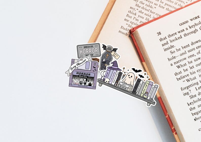 May include: A selection of Halloween-themed stickers. The stickers include a bookshelf, a tombstone, a floppy disk, and a sign that says "HORROR". The colour palette is purple, grey, and black, with a ghost and bats.