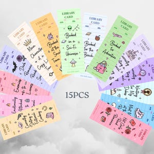 May include: Fifteen colorful library card-themed bookmarks with various designs and text. Each bookmark features a different color and design, including illustrations of a crown, a house, an alien, a beach bag, and a castle. Text includes "Main Character", "Booked in a Sci-Fi Universe", and "Booked for Adventure".