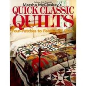 May include: A bed with a patchwork quilt, displaying a variety of colours and patterns. The quilt is draped over the bed, with a book titled "Quick Classic Quilts" visible in the image. The book cover has red and white text.