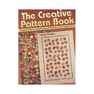 Puede incluir: Un libro titulado "The Creative Pattern Book" con el texto "Complete Patterns, Intriguing Ideas & Musings on the Creative Process" de Judy Martin. La portada presenta dos diseños de edredones con patrones de hojas en colores otoñales.