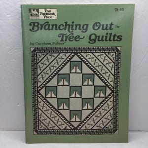 May include: A book titled "Branching Out & Tree Quilts" by Carolann Palmer. The cover is green with a quilt design featuring trees in a square pattern. The book has a logo that says "That Patchwork Place".