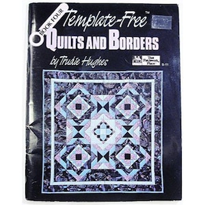 May include: A book titled "Template-Free Quilts and Borders" by Trudie Hughes. The cover features a geometric quilt design in shades of blue, purple, and black. The book is labeled "Book Four" and published by The Patchwork Place.