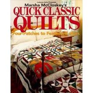 May include: A bed with a patchwork quilt, displaying a variety of colours and patterns. The quilt is draped over the bed, with a book titled "Quick Classic Quilts" visible in the image. The book cover has red and white text.
