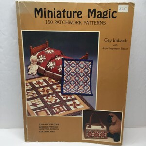 May include: A book titled "Miniature Magic" with the subtitle "150 Patchwork Patterns." The cover features images of miniature quilts, a doll, and a small bed. The author's name is Gay Imbach with Joyce Jesperson Bacon.