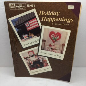 Puede incluir: Un libro marrón titulado "Holiday Happenings" de Christal Carter. La portada presenta tres fotos enmarcadas: una escena del 4 de julio con una bandera, una mesa de San Valentín y una escena de chimenea de la mañana de Navidad.