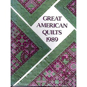 May include: A book cover titled "Great American Quilts 1989." The cover features a patchwork design in shades of green and purple, with a white diamond-shaped area containing the title and year.