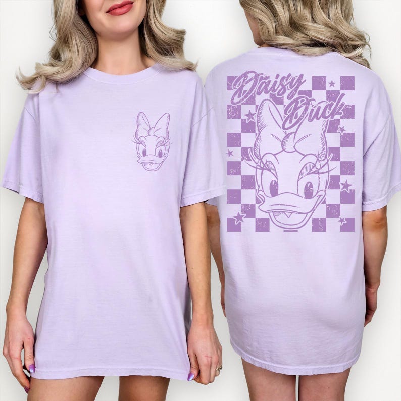 Puede incluir: Una camiseta de color lila claro con un gr&aacute;fico de Daisy Duck en la parte delantera y trasera. La parte delantera tiene una peque&ntilde;a cara de Daisy Duck, mientras que la parte trasera tiene un dise&ntilde;o m&aacute;s grande con las palabras "Daisy Duck" y un patr&oacute;n de cuadros.