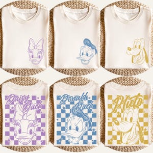 Puede incluir: Camisetas de color crema con los personajes de Disney Daisy Duck, Donald Duck y Pluto. Las camisetas tienen dise&ntilde;os gr&aacute;ficos de las caras de los personajes. Algunas camisetas tienen el nombre del personaje impreso.